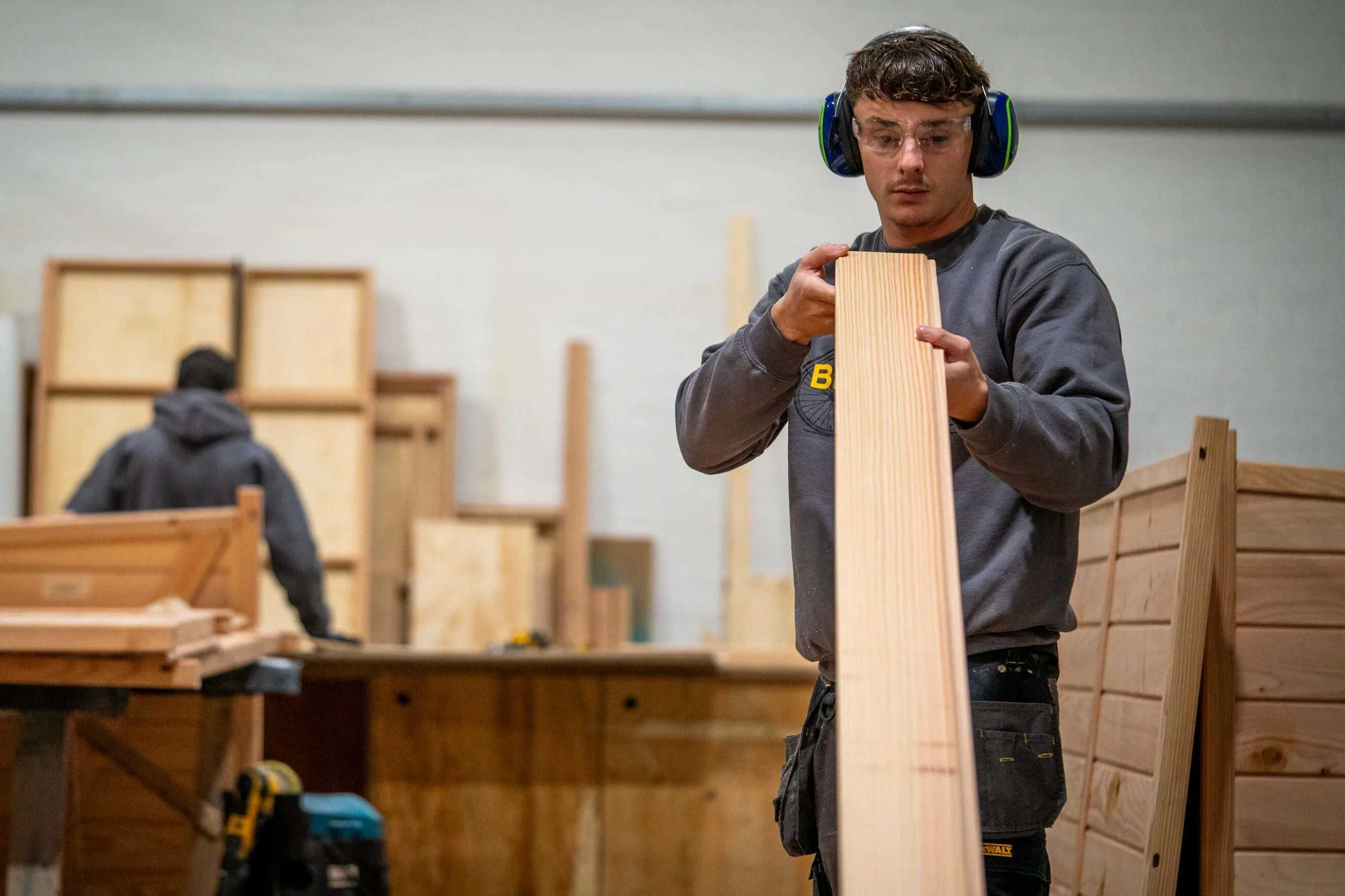 A carpenter looks down the length of a board to check it's straight and unblemished